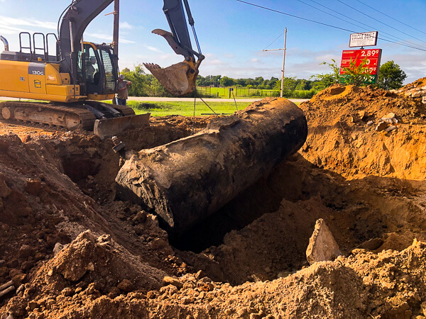 Excavator lifting large underground tank